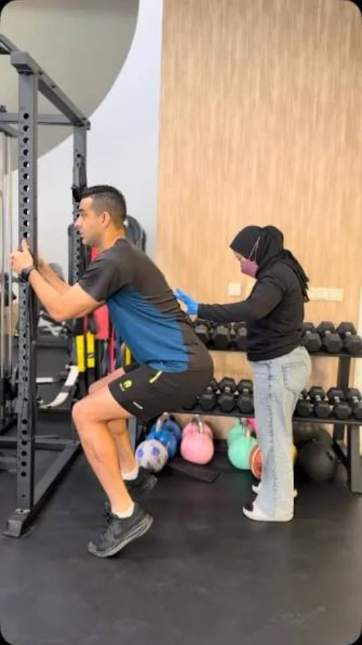 Latihan squat didampingi fisioterapis di area latihan